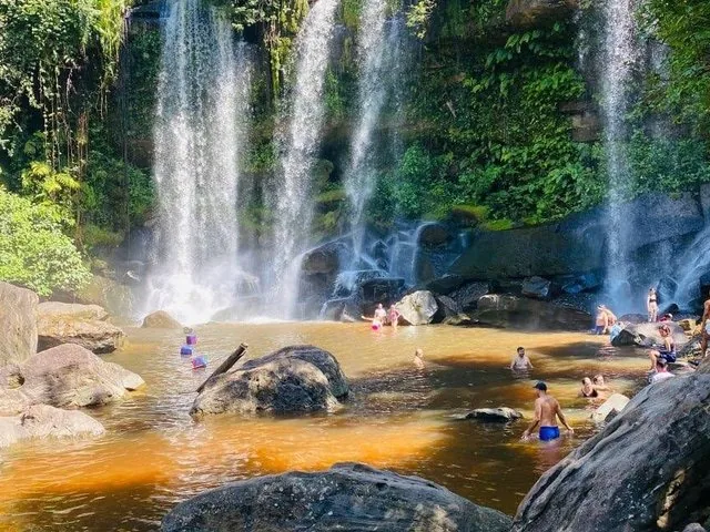Personas nadando y relajándose en la poza al pie de la cascada de Kulen