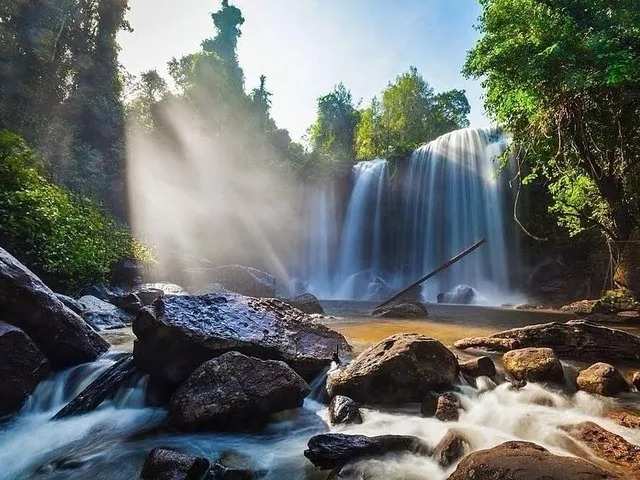 Sunlight streaming through the mist at the base of Kulen Waterfall