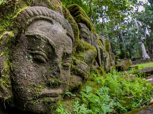 Mit Moos bedeckte Steingesicht-Skulptur an einer antiken Tempelruine