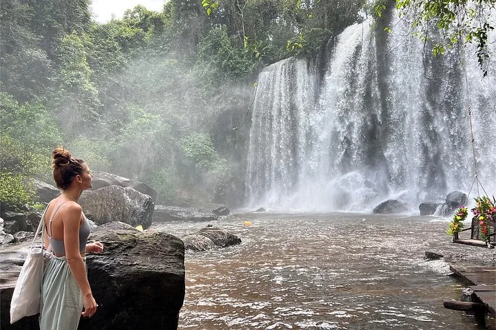 Mujer de pie junto al río mirando hacia arriba la majestuosa cascada de Kulen