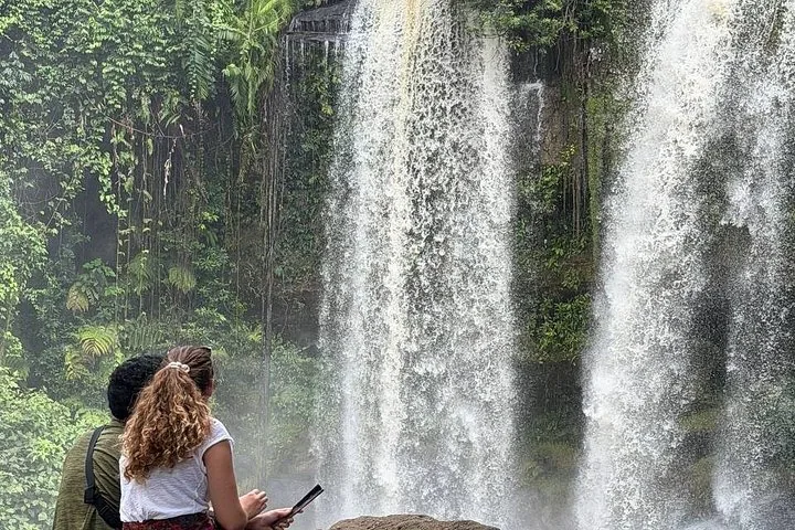 Pareja sentada en una roca admirando el agua que cae de la cascada de Kulen